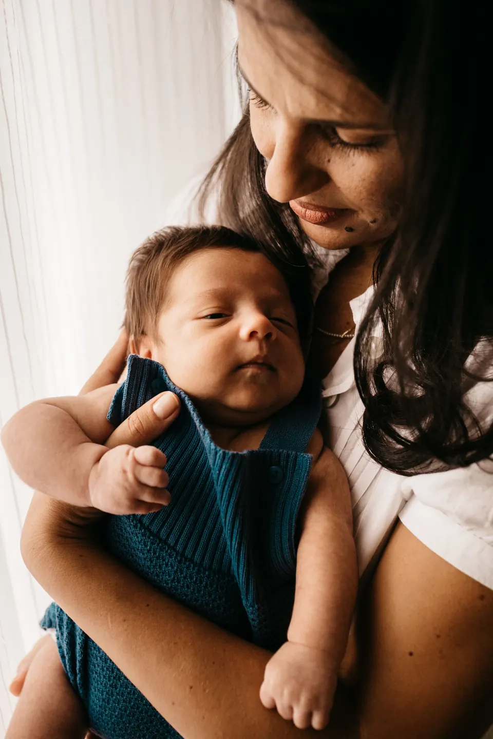 Maa newborn ke sar ko sahara dete hue usay qareeb thame hue hai.